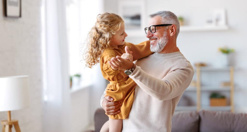 Grandfather and granddaughter dancing in the livingroom